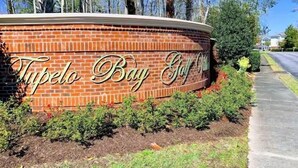 A brick sign with the text "Tipelo Bay Golf Club" surrounded by greenery and palm trees. - Beautiful Beach / Golf Villa (Garden City)
