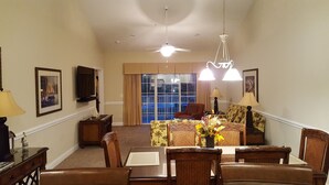 A spacious living room with a dining area, large windows, and a ceiling fan. - Beautiful Beach / Golf Villa (Garden City)