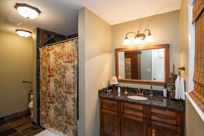 Une salle de bain avec un rideau de douche, un lavabo, un miroir et des meubles en bois.