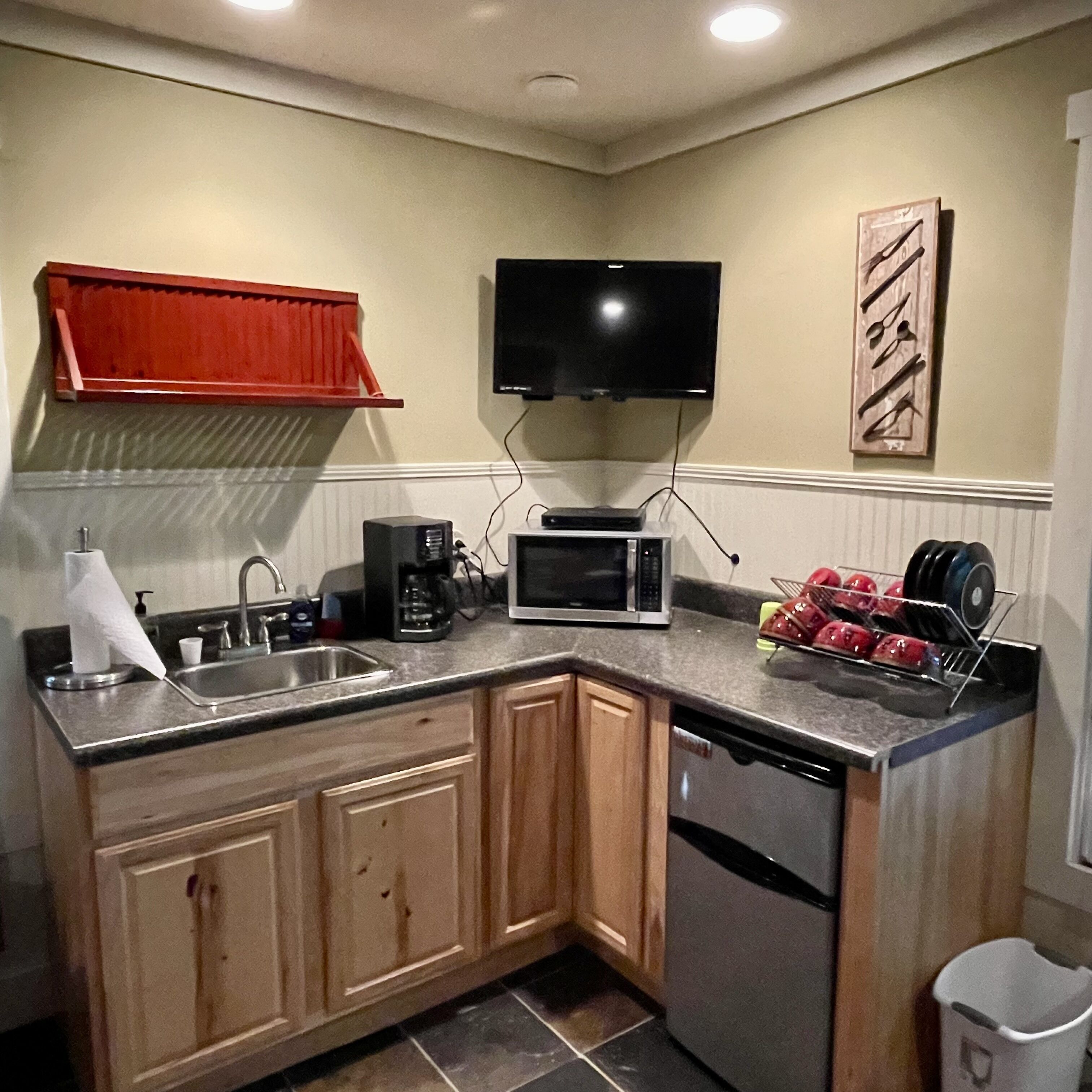 A compact kitchen with a microwave, coffee maker, and a small sink.