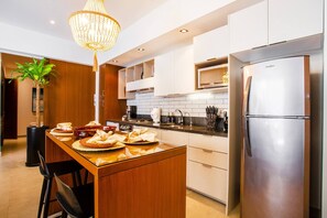 A modern kitchen with a central island, stainless steel appliances, and a chandelier.