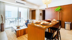 Une cuisine moderne dotée d’un îlot central, d’un coin repas avec des chaises, d’un lustre et offrant une vue sur l’extérieur.