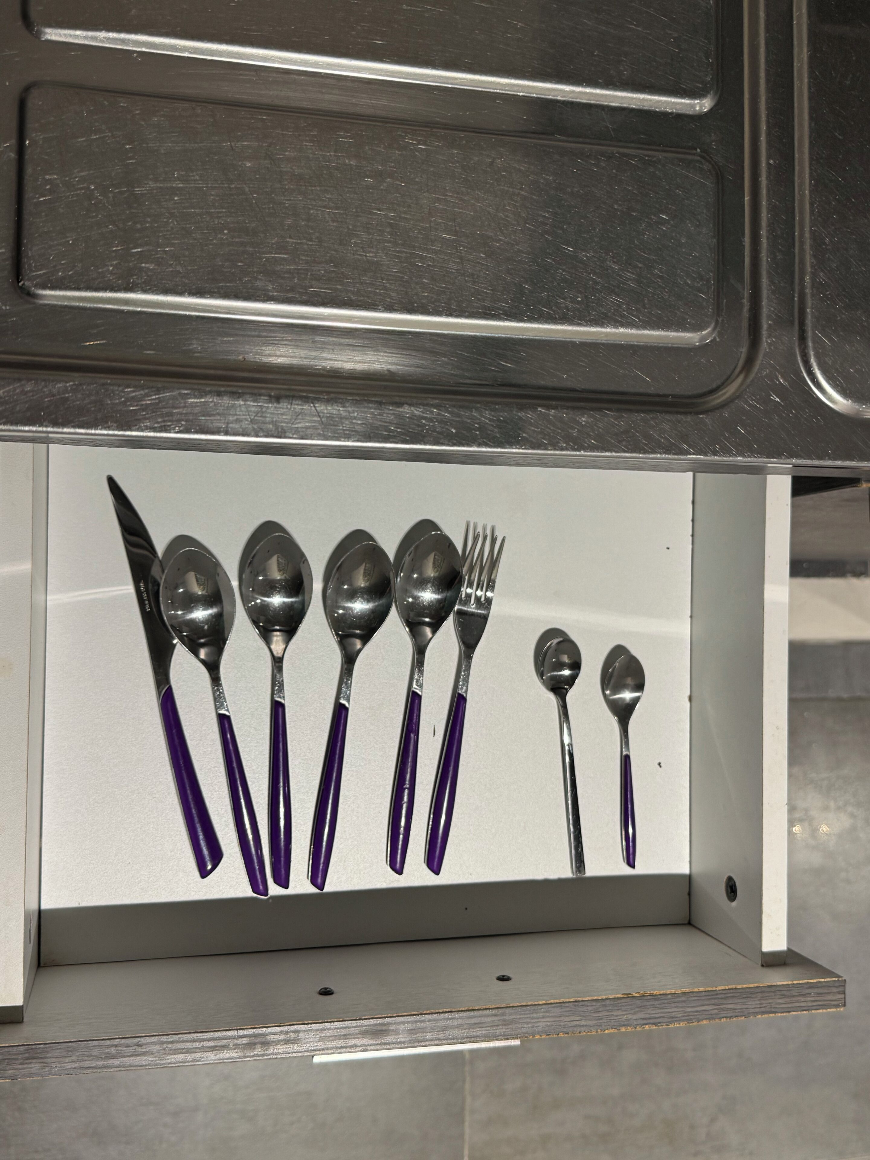 A drawer containing various utensils including spoons, forks, and knives.