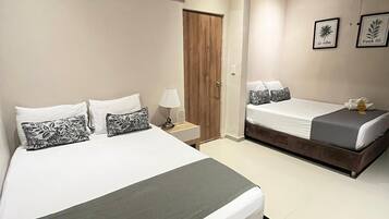 Quarto de hotel com duas camas, um ventilador de teto e uma porta.