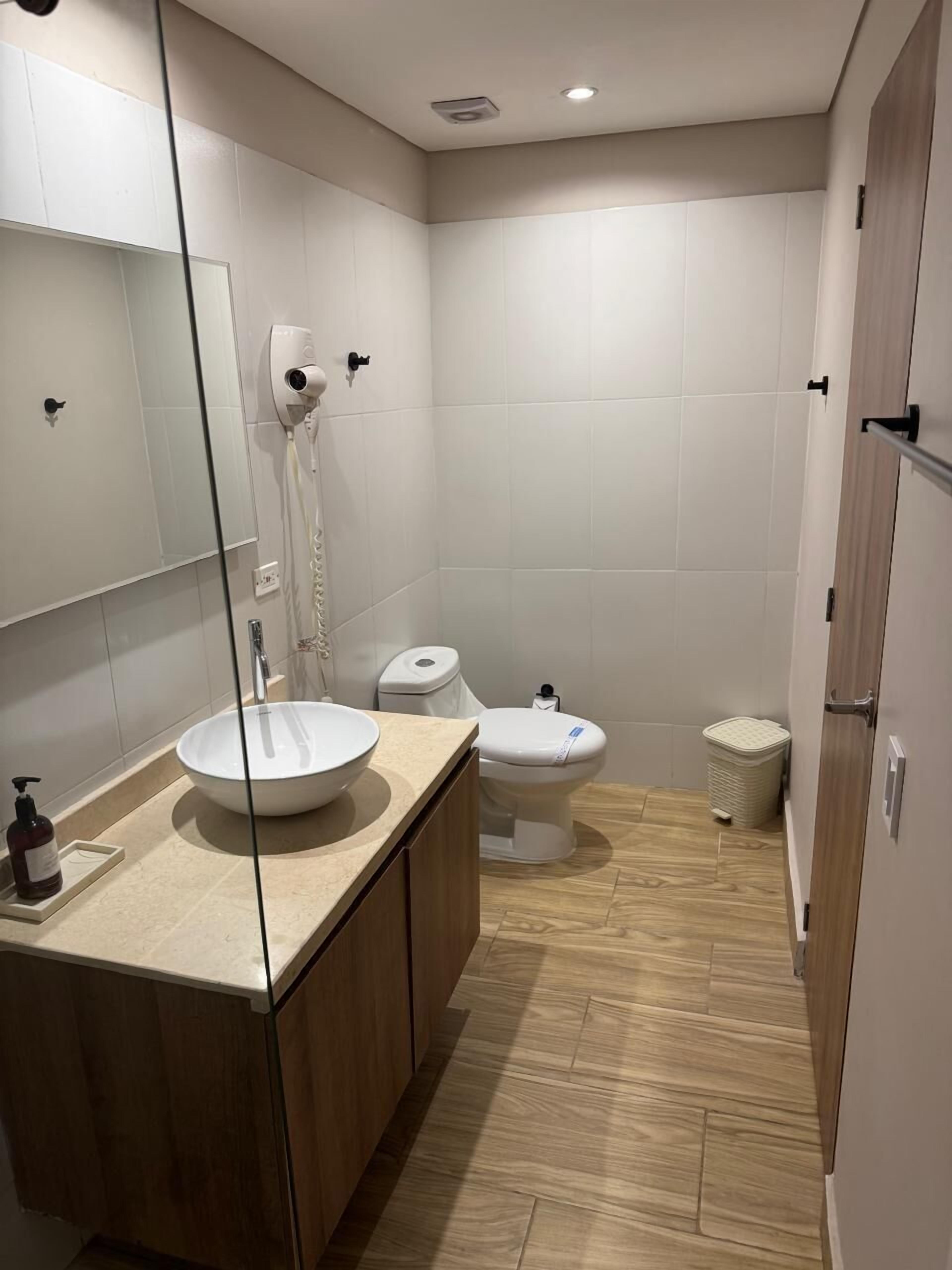 Ein modernes Badezimmer mit großem Spiegel, Waschbecken in Weiß und Toilette.