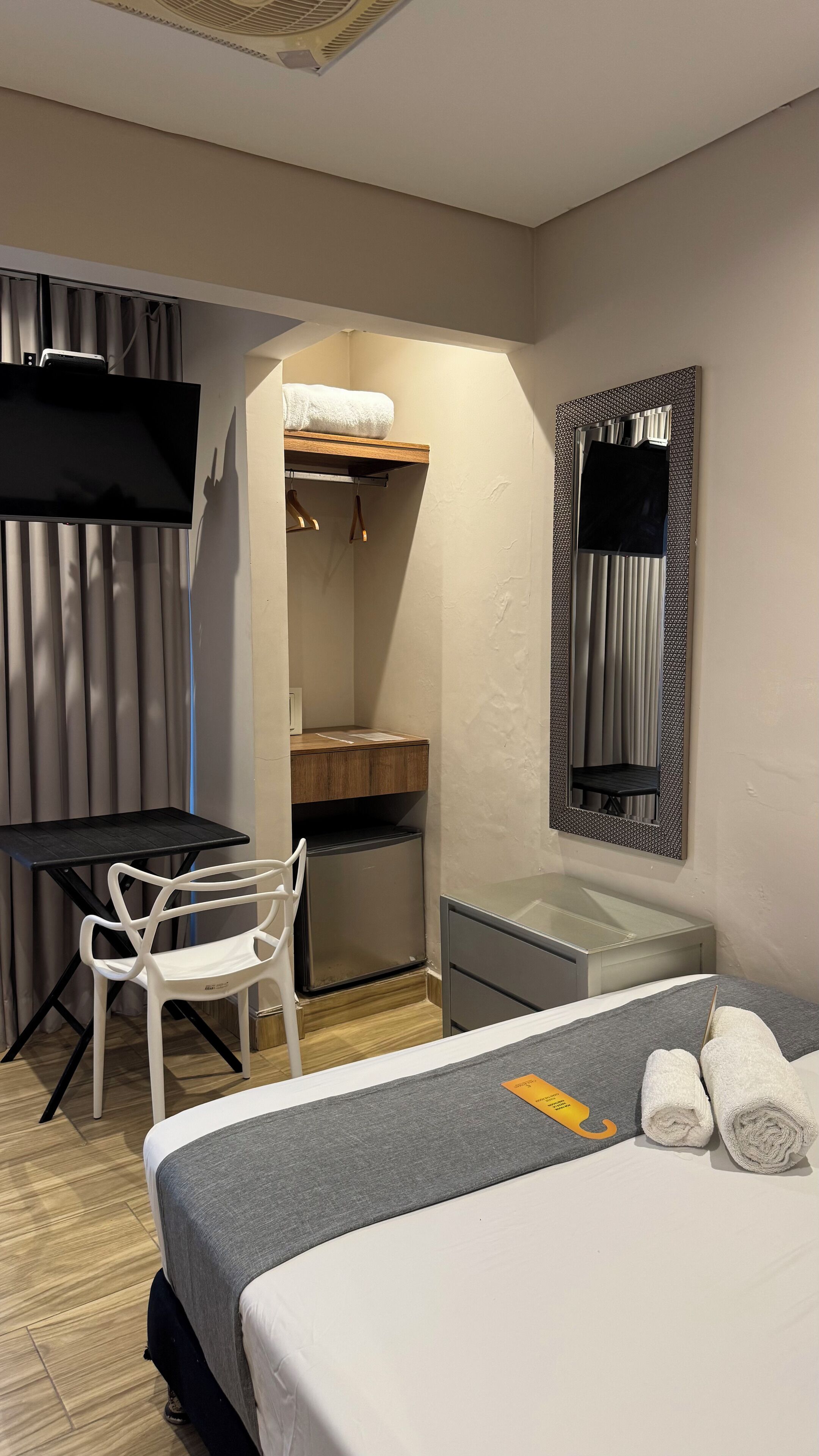Una habitación de hotel con una cama, un escritorio, una silla, un armario y un televisor.