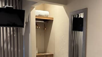Una habitación de hotel con una cama, un escritorio, una silla, un armario y un televisor.