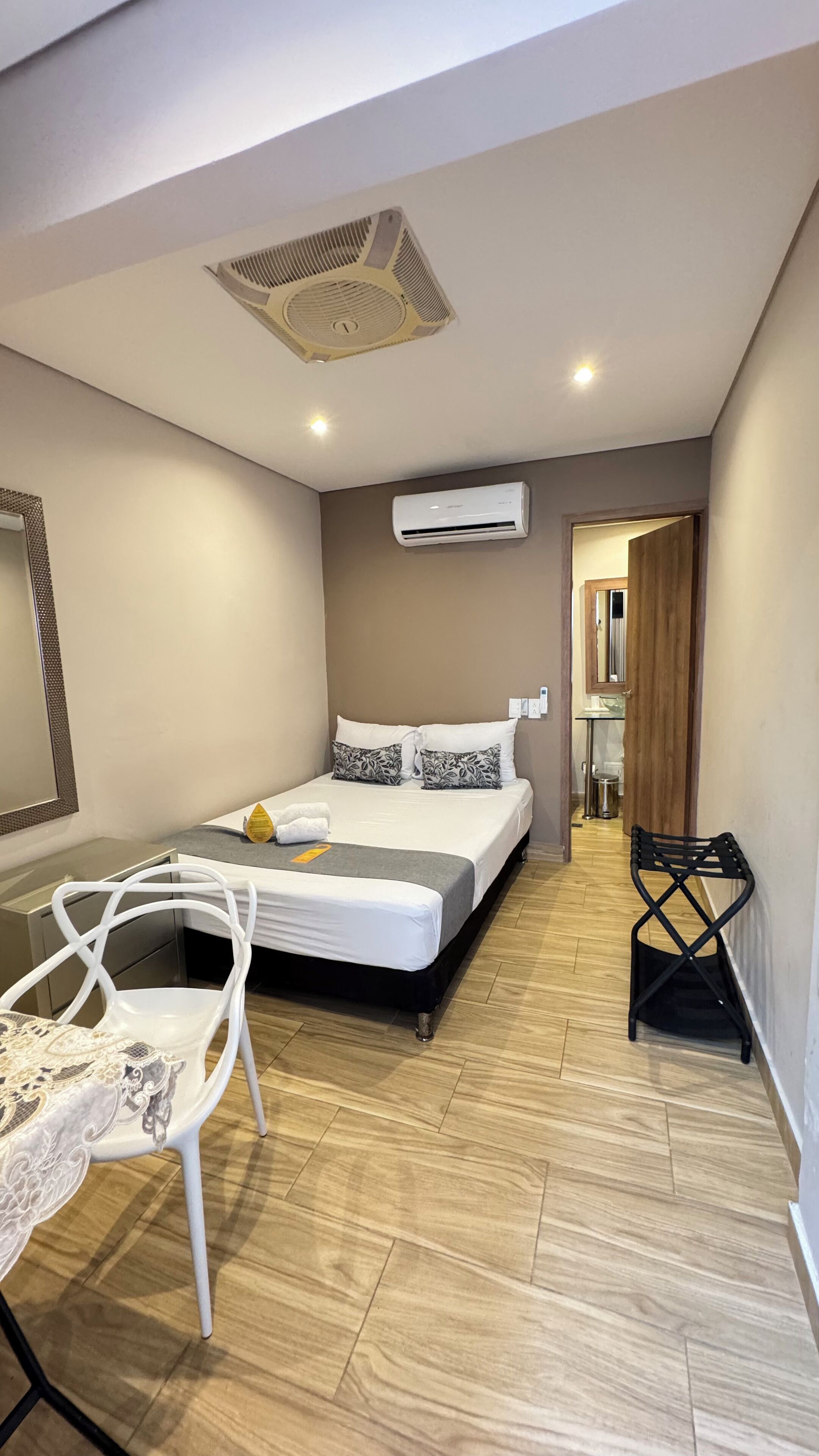 A modern bedroom with a bed, a desk, and an air conditioning unit.