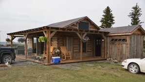 Une cabane en bois rustique, dotée d’une véranda, d’un espace salon extérieur et d’un garage.