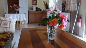 Un tavolo da pranzo con un vaso di fiori, una sedia di legno e una cucina sullo sfondo.