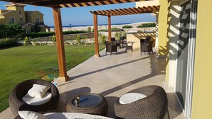 A covered outdoor seating area with wicker furniture and a view of the sea. - Diplomats Villa at Diplo4 MV Rass El Hekma (El Dabaa)