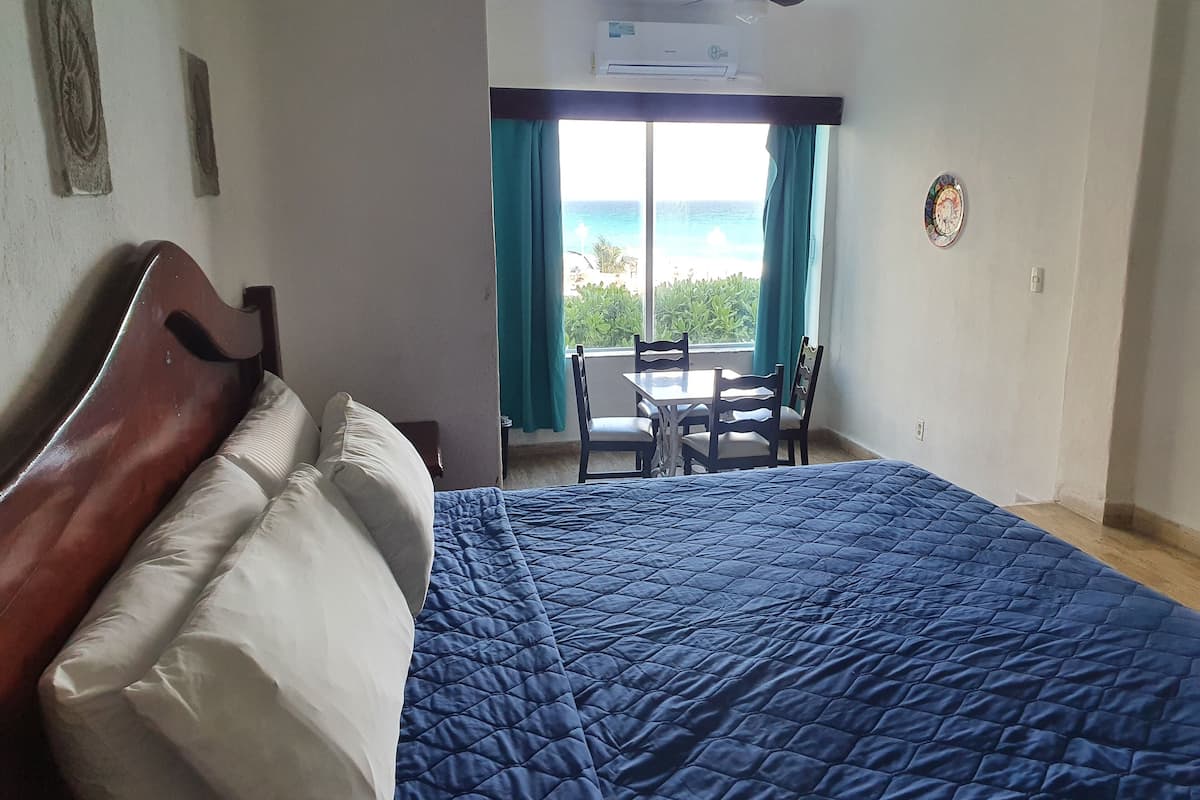 Une chambre à coucher avec un lit, un ventilateur de plafond, une fenêtre avec des rideaux et une vue sur l’océan.