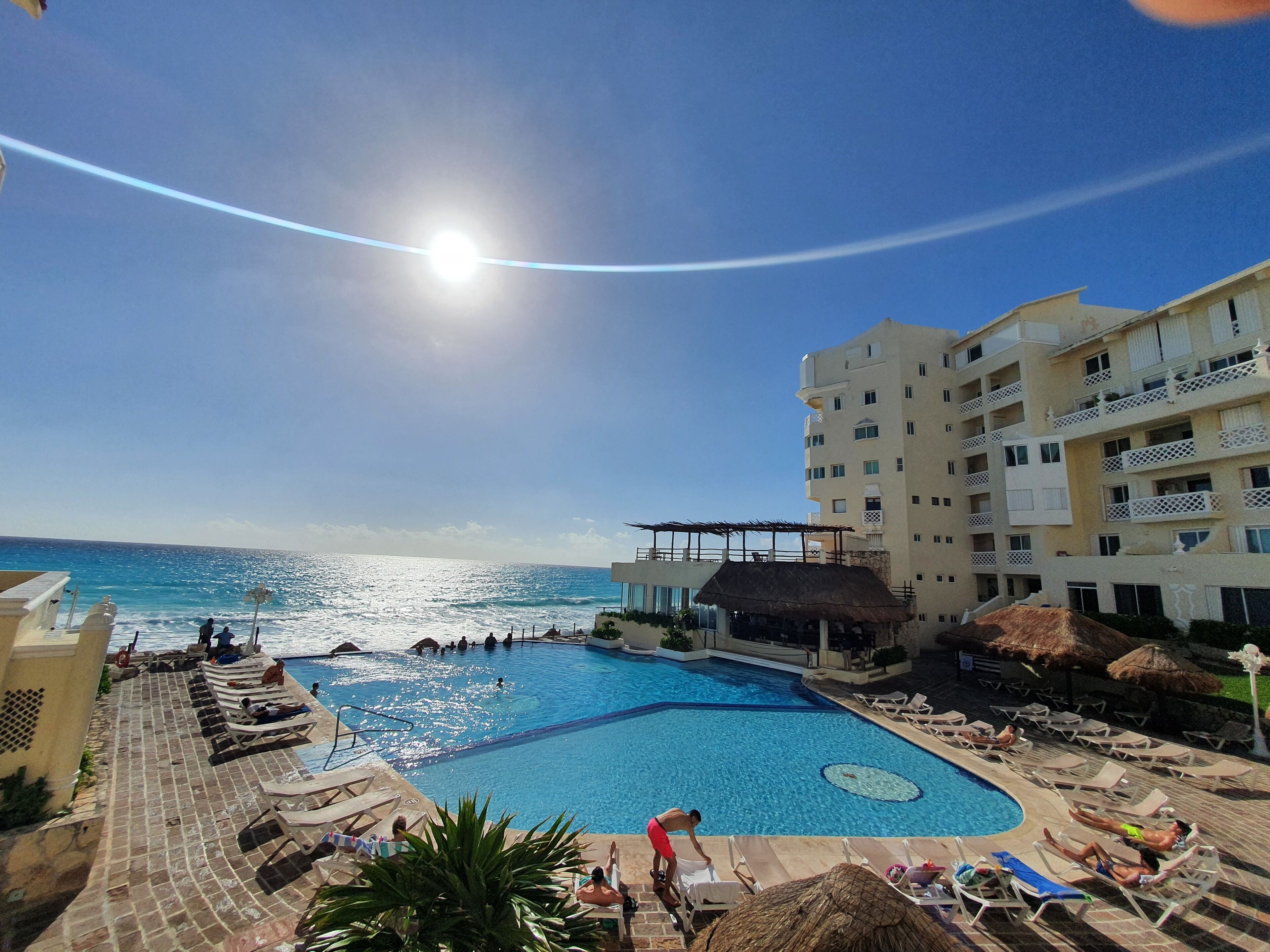 A swimming pool with lounge chairs and a view of the ocean.