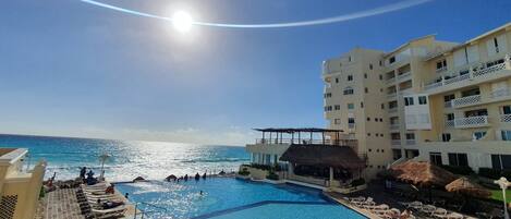A swimming pool with lounge chairs and a view of the ocean.