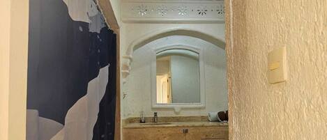 A narrow bathroom with a shower, a sink, and a toilet.