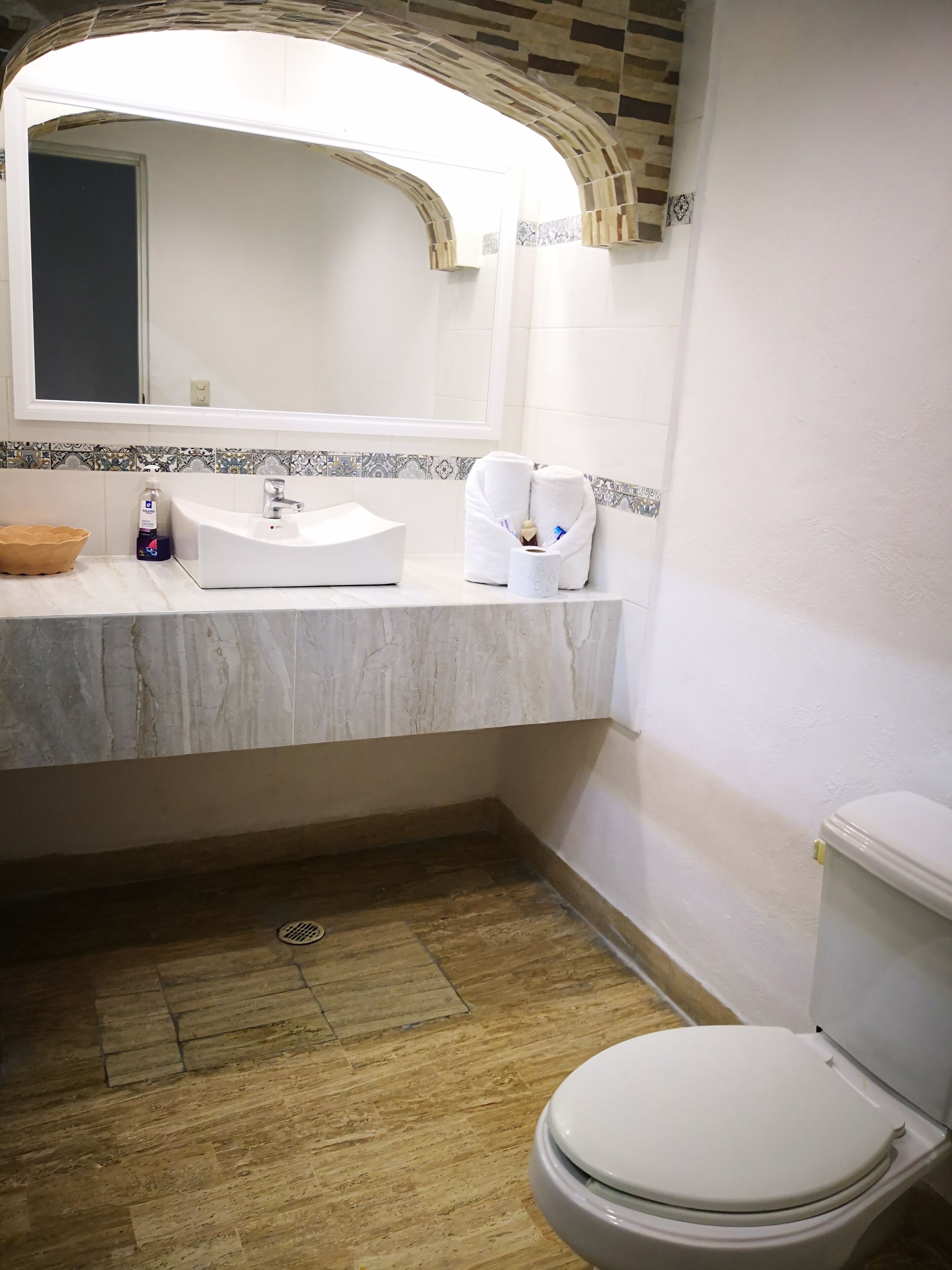 A bathroom with a white sink, a mirror, and a toilet.