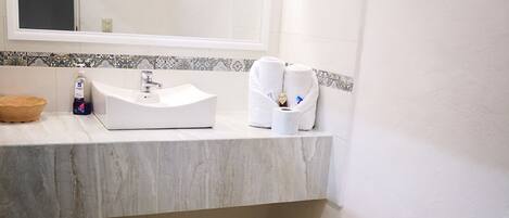 A bathroom with a white sink, a mirror, and a toilet.