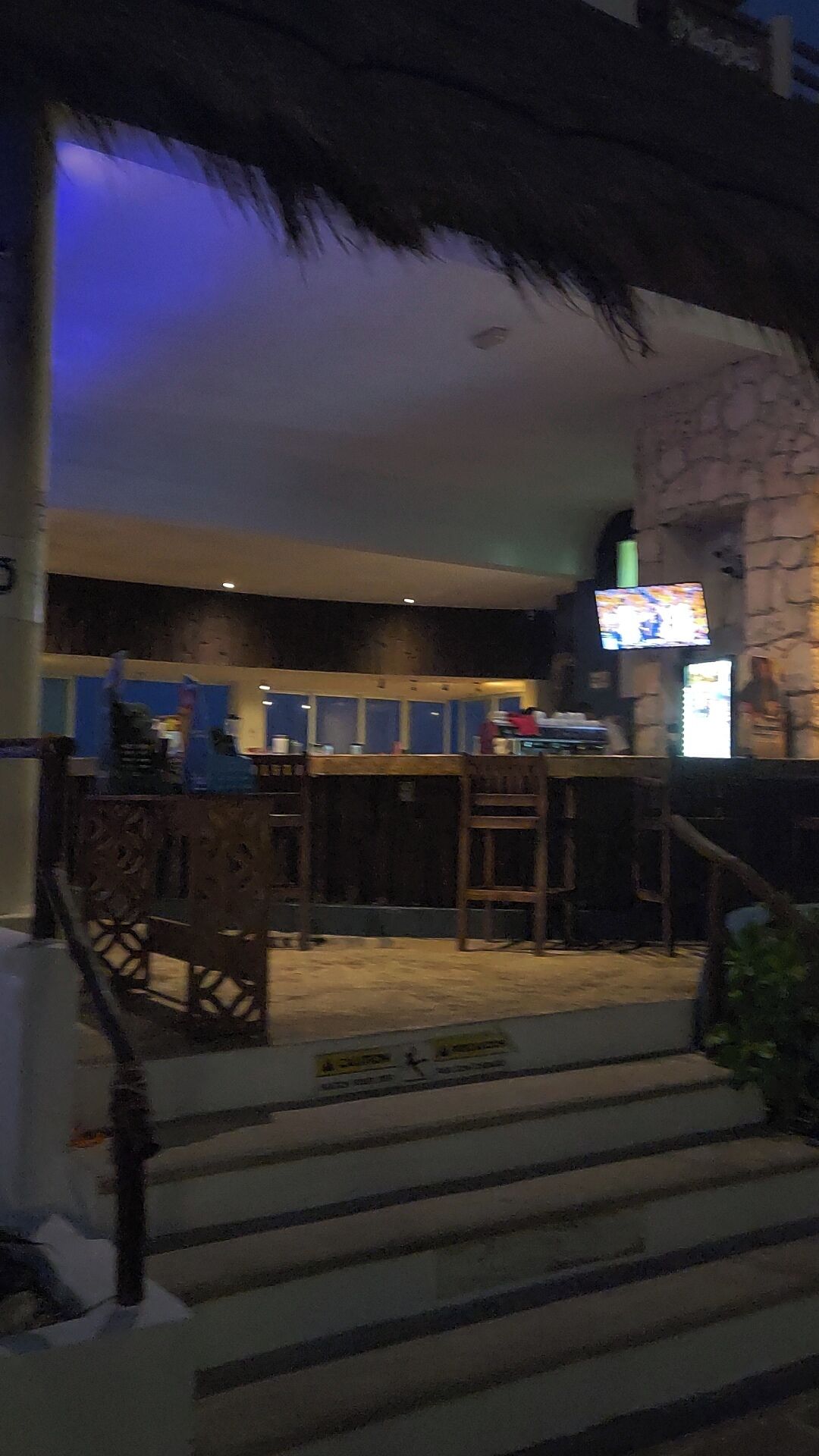 A bar area with a stone wall, a television, and a staircase leading to a lower level.