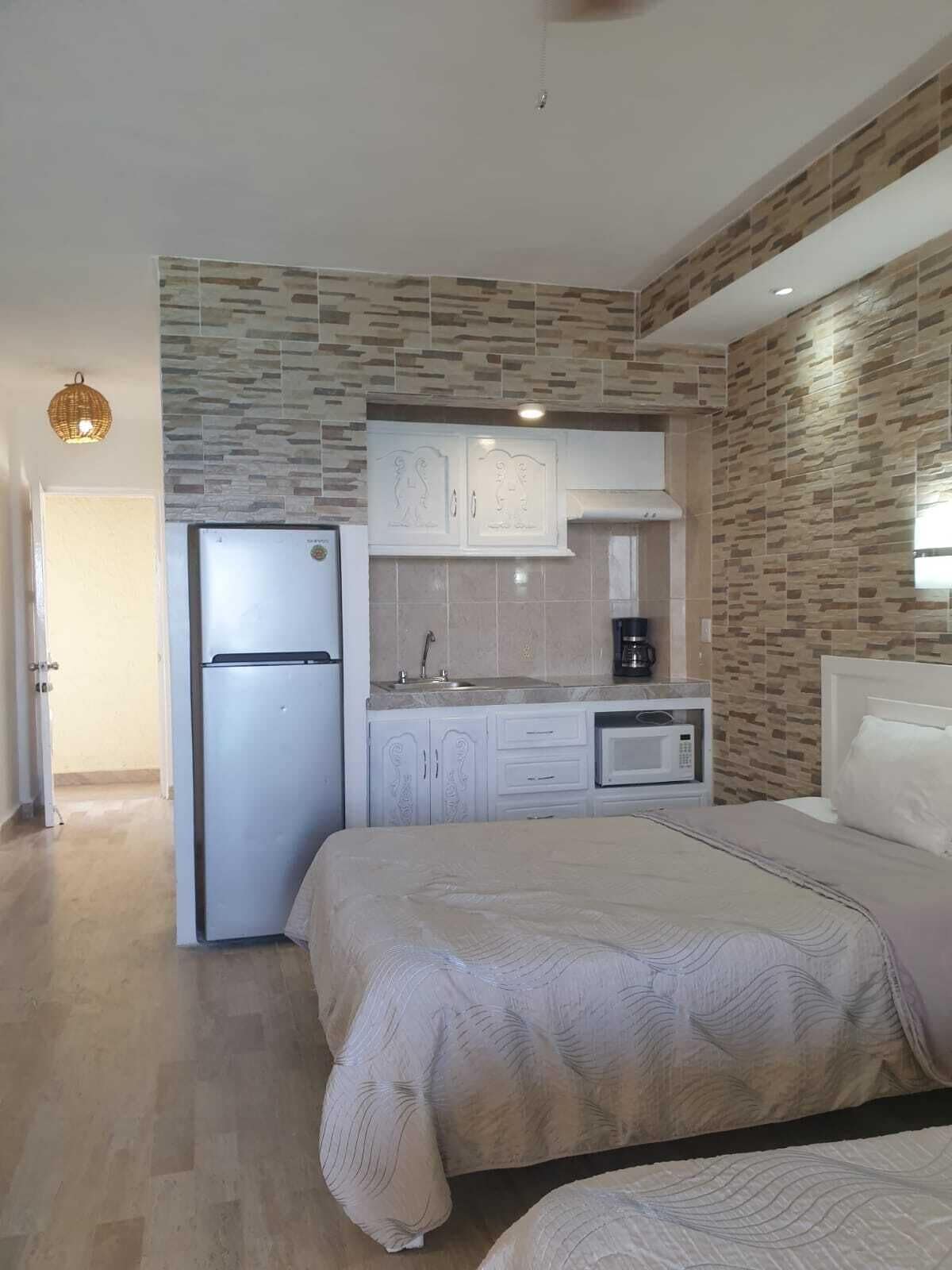 Une chambre d’hôtel compacte comprenant une kitchenette, un lit et une petite salle de bain.