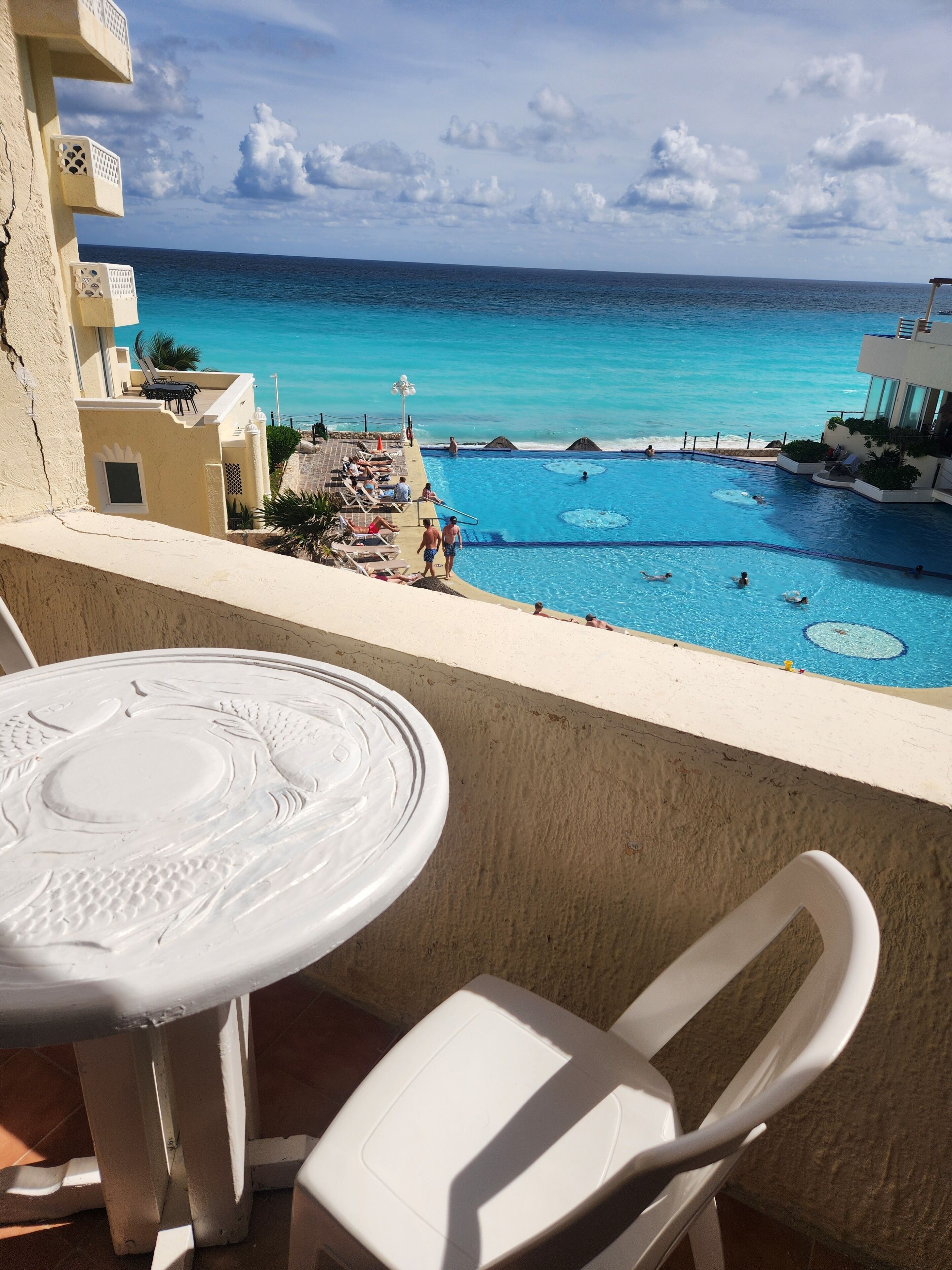 Un balcon avec vue sur une piscine et l’océan.