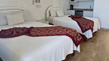 A hotel room with two beds, a ceiling fan, a microwave, and a small kitchenette.