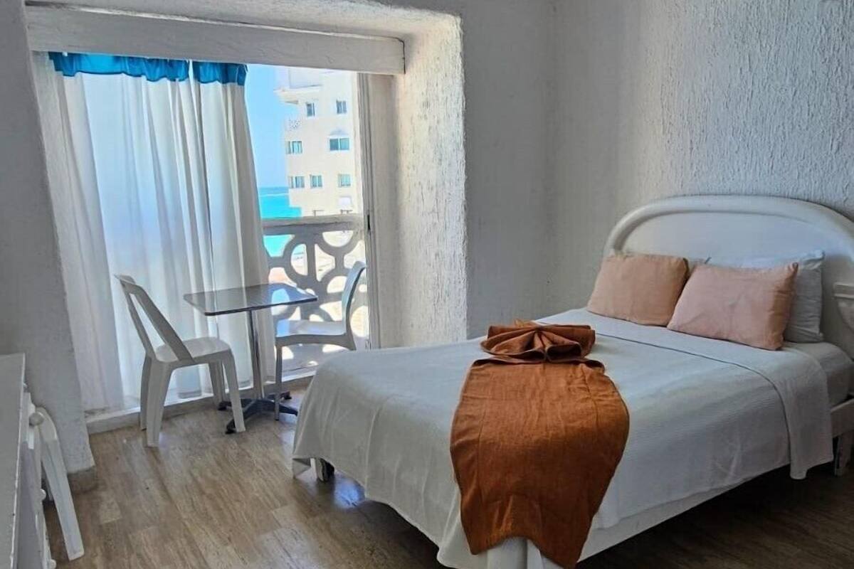 Une chambre avec un lit, une chaise, une table et un balcon offrant une vue.