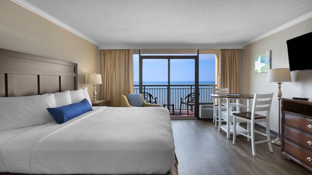 Une chambre d’hôtel avec un grand lit, un bureau et une vue sur l’océan.
