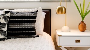 Una camera da letto con un letto, un comodino, una lampada e una pianta in vaso.
