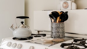 Una cucina con un piano cottura bianco, un bollitore e un contenitore con utensili.