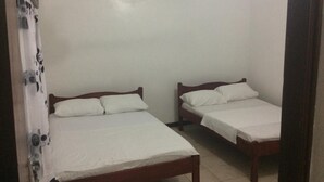 A small, clean room with two wooden beds, white bedding, and a ceiling fan. - SHREE ENCLAVE WEST COURT (Mombasa)