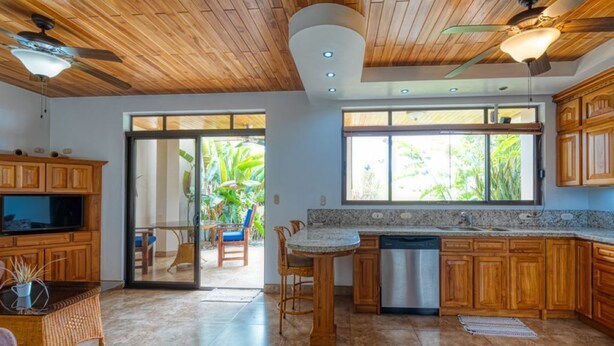 A spacious kitchen with wooden cabinets, a granite countertop, and a large window providing natural light. - Private Garden, Walk Out to Community Pool, Beautiful 1 Bedroom 1 Bath Condo (San Buenas)