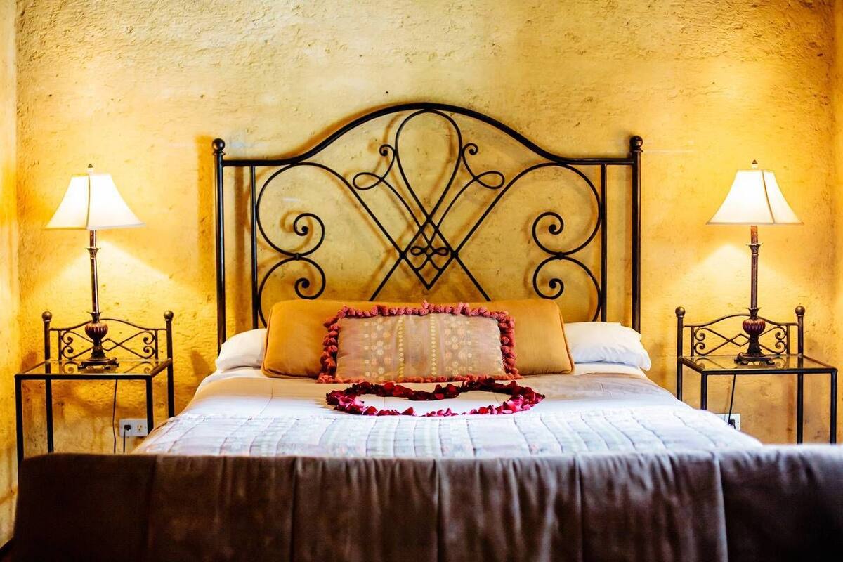 A bed with a metal headboard, two bedside tables with lamps, and a decorative pillow.