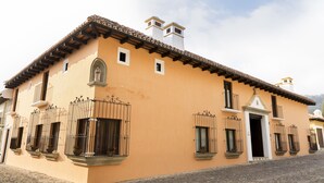 Un edificio tradicional con techo de tejas, varias ventanas con barandillas de hierro y una calle empedrada.
