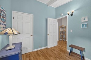 Ein Zimmer mit zwei weißen Türen, einer Holzbank, einem Wandregal und einer Wandleuchte.
