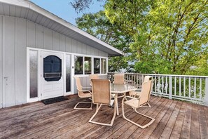 Eine überdachte Terrasse mit Esstisch und Stühlen, eine weiße Tür und ein weißer Geländer.