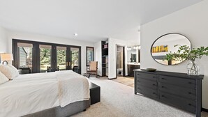 Une chambre à coucher moderne avec un grand lit, une commode et un miroir.