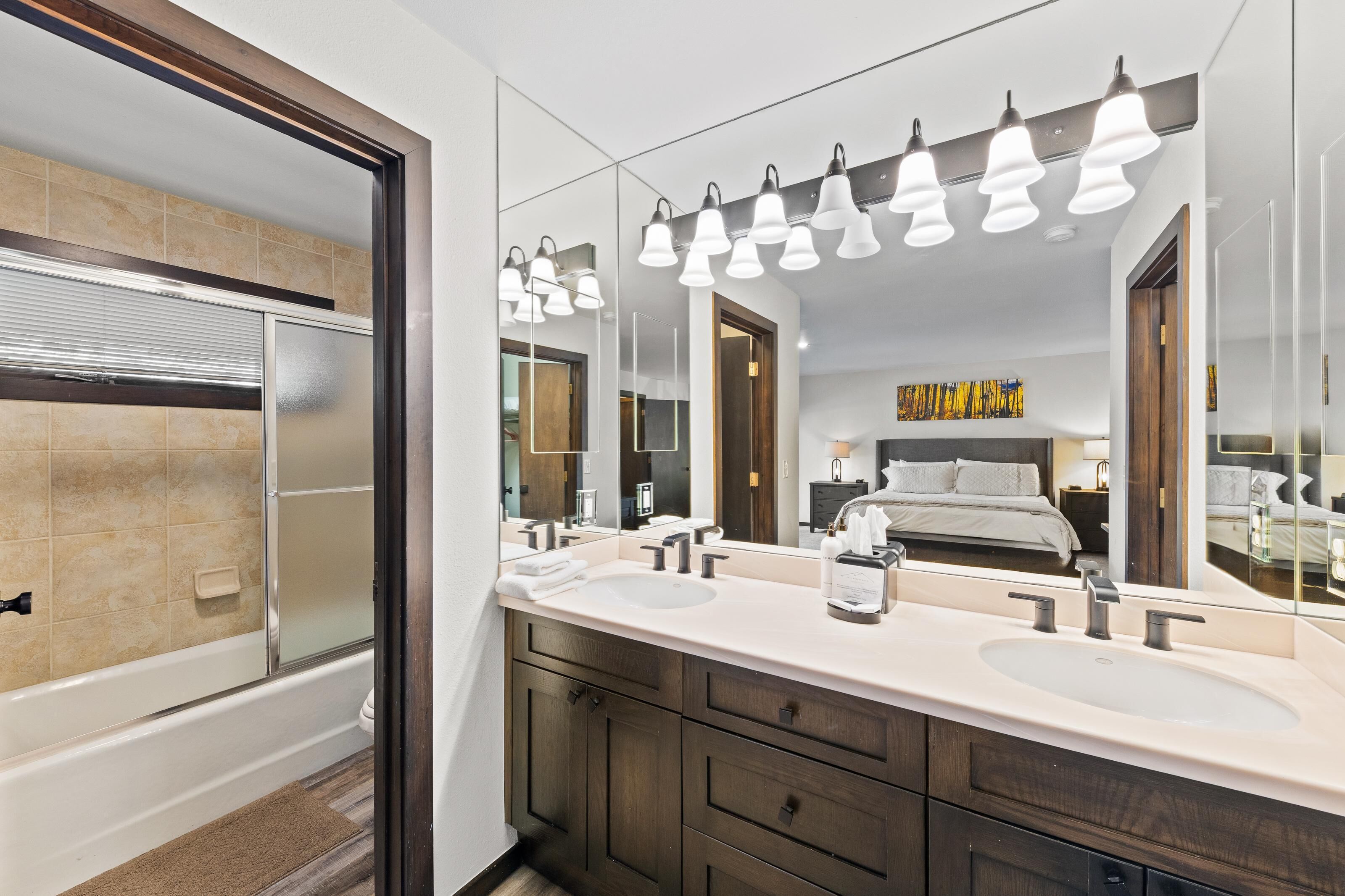 A modern bathroom with two sinks, a large mirror, and a shower.