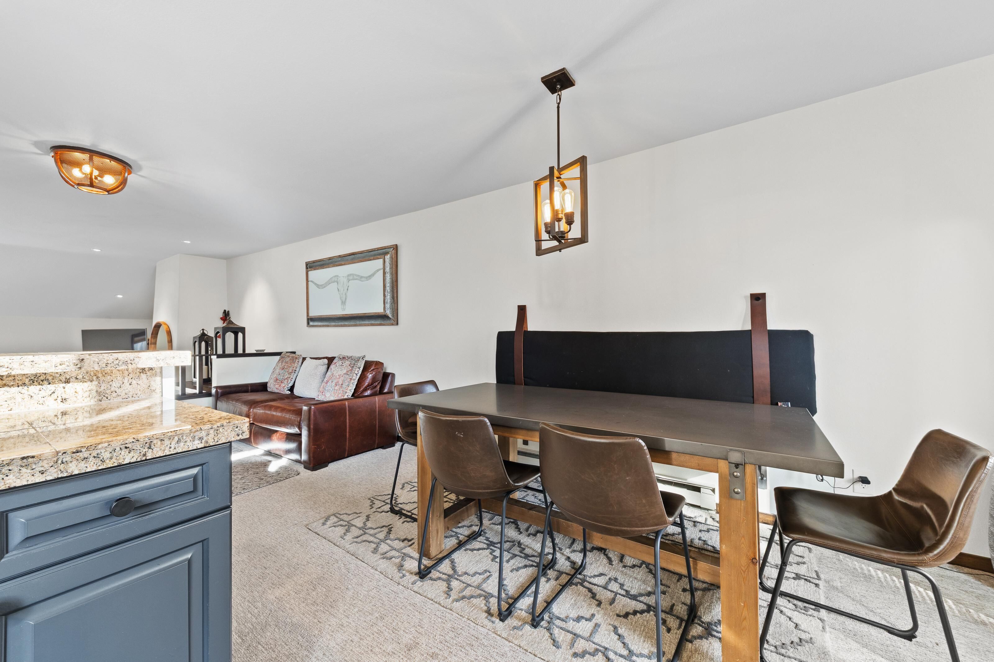 A dining area with a wooden table, brown leather chairs, and a patterned rug.