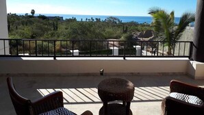 A balcony with wicker furniture, a railing, and a view of the ocean and greenery. - Gorgeous 2 1/2 Bedrooms  House with a private pool and a Spectacular View (cabo san lucas)