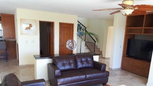 A living room with a dark brown sofa, a wooden coffee table, and a television on a wooden stand. - Gorgeous 2 1/2 Bedrooms  House with a private pool and a Spectacular View (cabo san lucas)