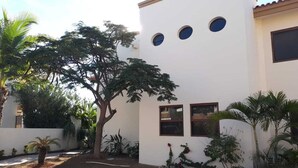 A white building with three circular windows and a small balcony. - Gorgeous 2 1/2 Bedrooms  House with a private pool and a Spectacular View (cabo san lucas)