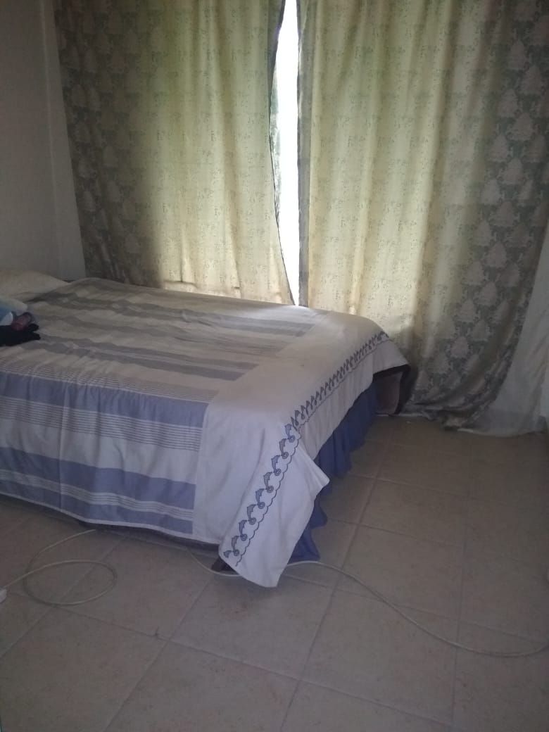 A bedroom with a bed, curtains, and a tiled floor.