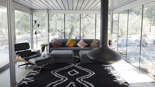 En moderne stue med en sofa, skammel og en stor gulvlampe.