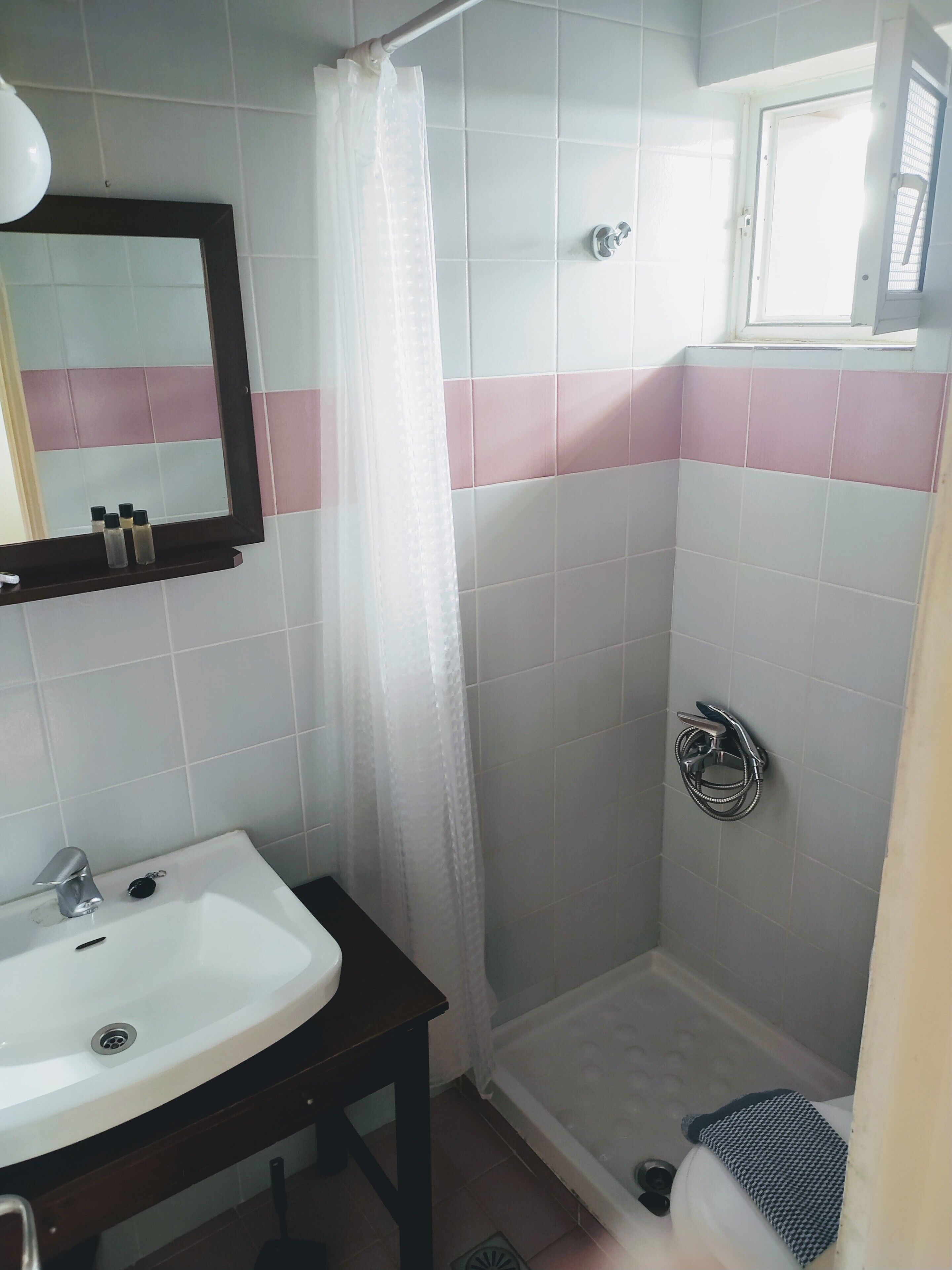 A bathroom with a sink, mirror, shower, and toilet.