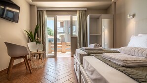 Une chambre d’hôtel avec un lit, une chaise, une petite table avec une plante et un téléviseur fixé au mur.