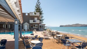 Une terrasse en bois avec des sièges extérieurs, une piscine et une vue sur la mer.