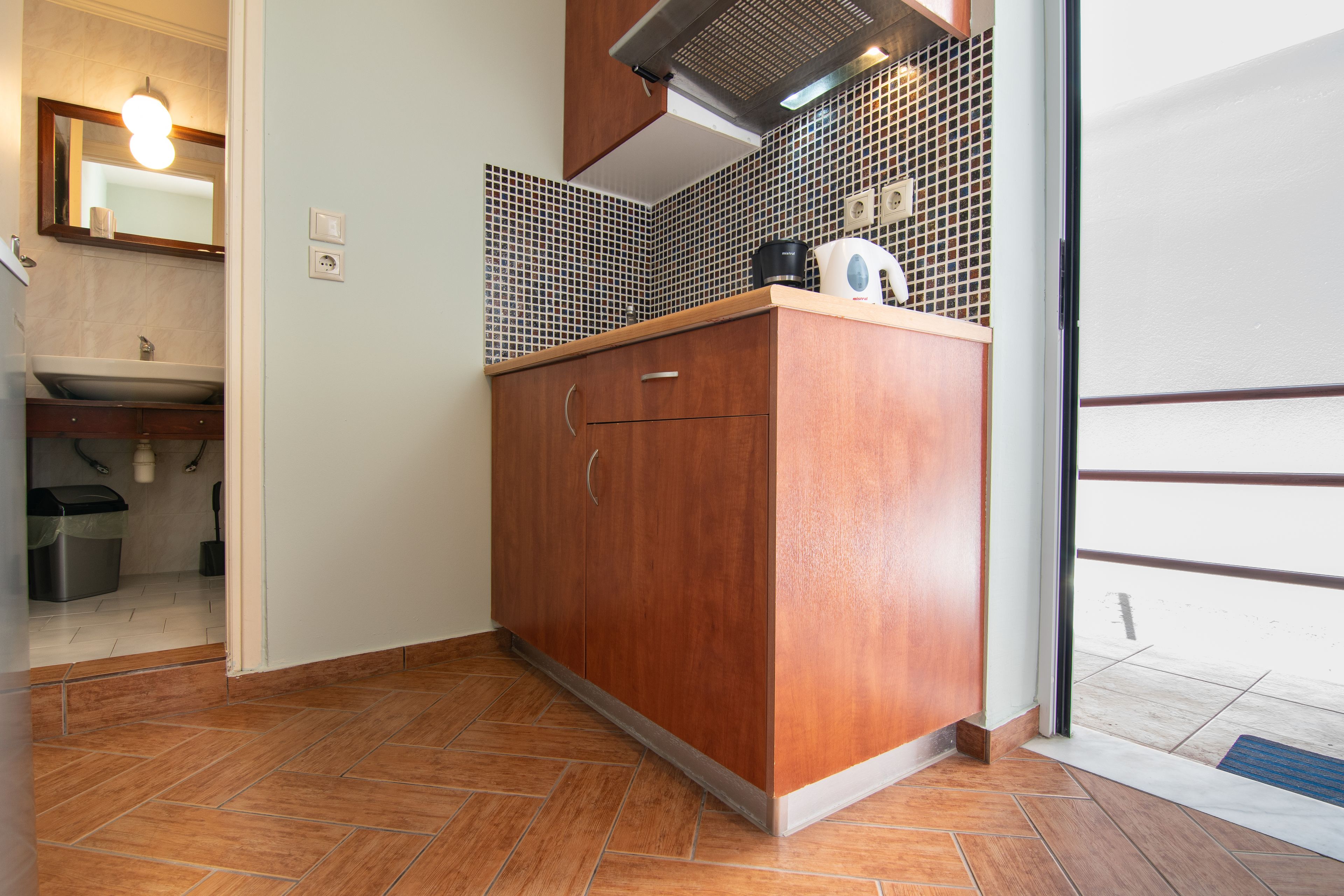 A compact kitchen with a wooden cabinet, a sink, and a tiled backsplash.