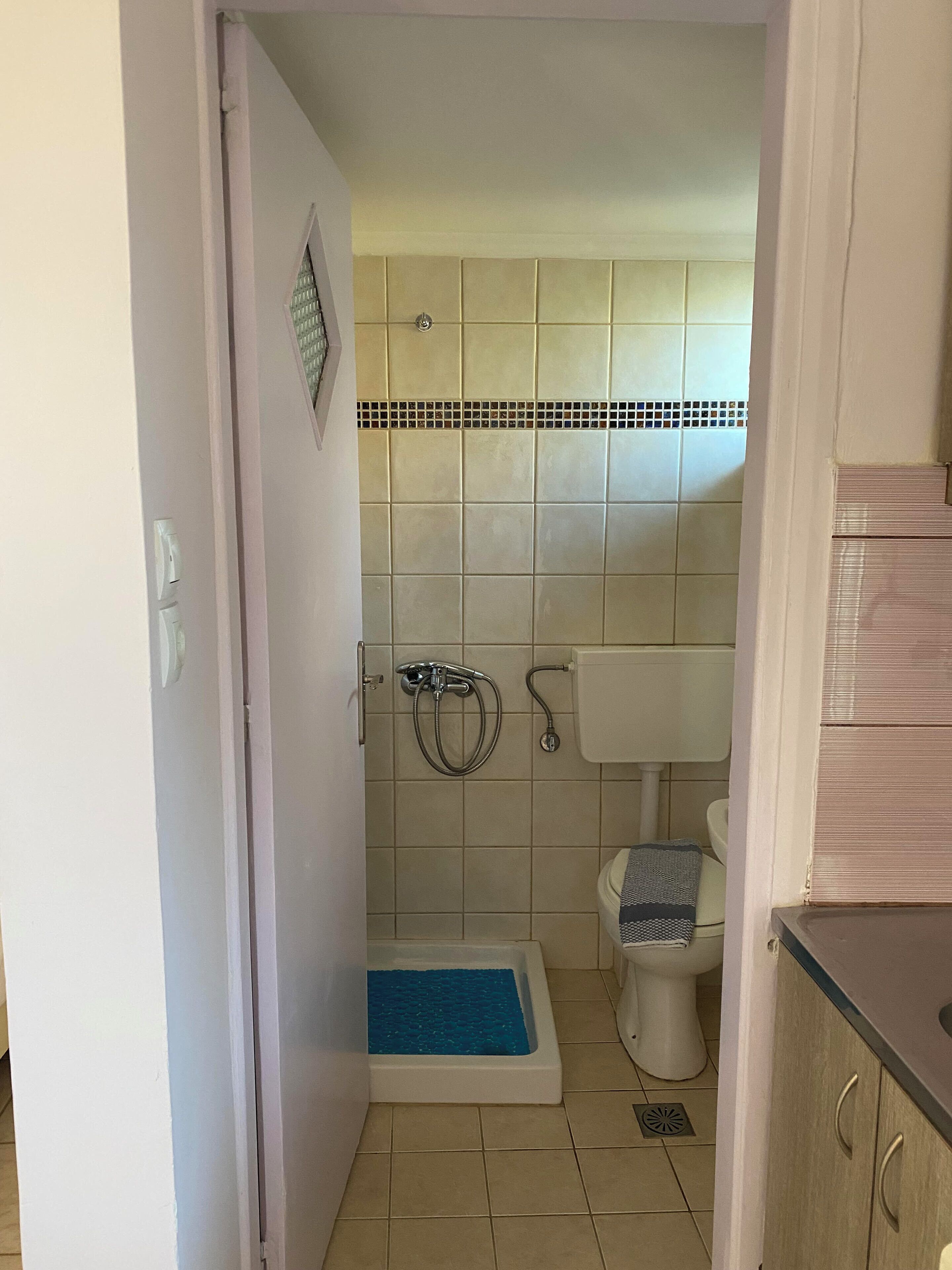 A small bathroom with a shower, toilet, and a sink.