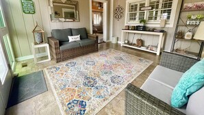 A cozy living room with a wicker sofa, a patterned rug, and a ceiling fan. - Cozy Cottage Wooded Retreat (Hendersonville)