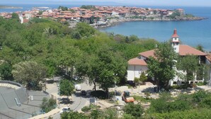 A coastal town with a prominent church tower, a marina, and a mix of residential buildings. - The great view and the perfect leisure time (Sozopol)